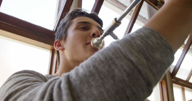 Young musician playing trumpet indoors - Download Free Stock Images Pikwizard.com