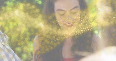 Smiling woman looking downward amid golden bokeh in sunlit park lifestyle portrait