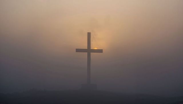 Glowing Cross Silhouette at Misty Sunrise