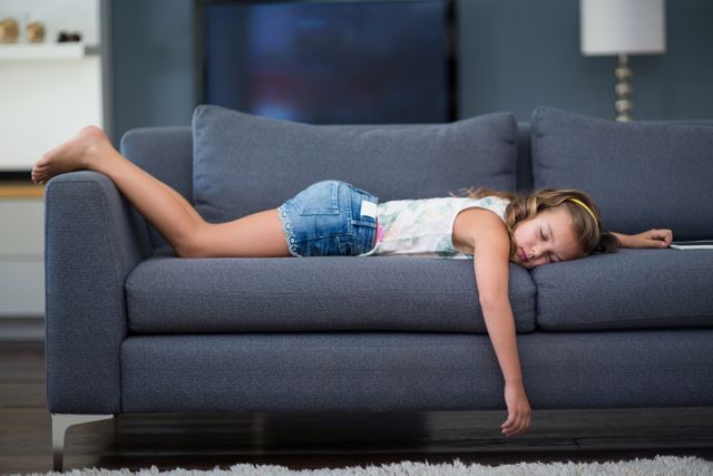 Girl sleeping on sofa in living room at home
