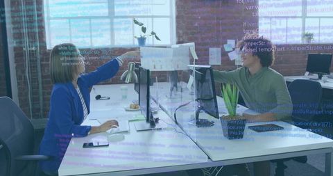 Colleagues Collaborating Across Desk Sharing Printout in Bright Industrial Open-Plan Office