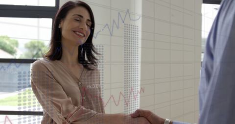 Business professionals shaking hands with overlay of financial data