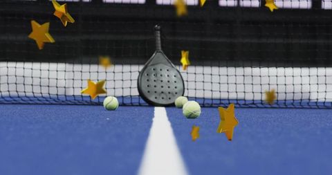 Black padel racket leaning against net with scattered tennis balls and gold stars on blue court