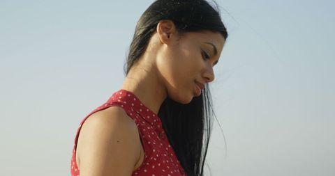 Woman in red polka dot dress looking thoughtful outdoors