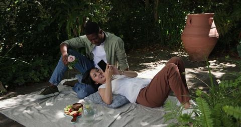 Couple Enjoying Picnic with Smartphone in Relaxing Outdoor Setting