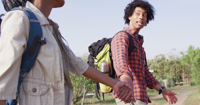 Happy african american couple with backpacks, hiking together on sunny day, slow motion. Lifestyle, countryside and nature concept.