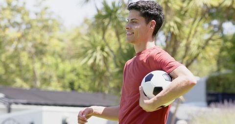 Joyful Young Man Holding Soccer Ball in Sunny Garden