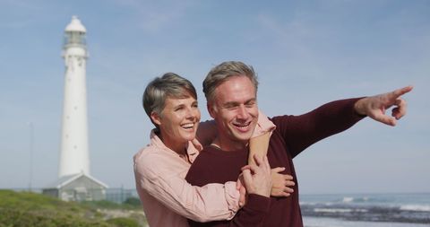 Joyful Senior Couple Embracing by Coastal Lighthouse