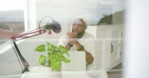 African american podcaster recording in bright home studio laptop and boom microphone