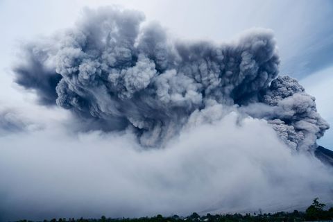 Massive volcanic eruption with ash cloud and steaming plumes