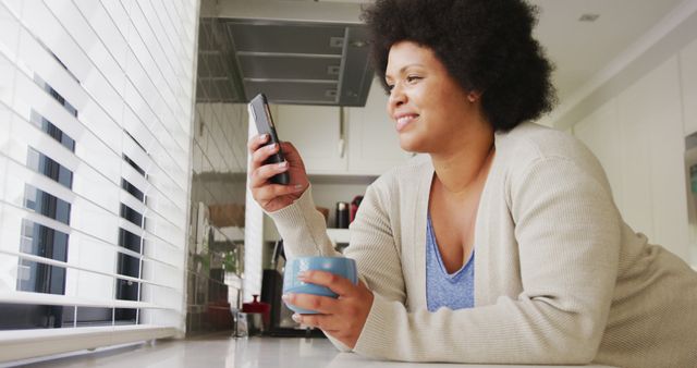 Smiling African American Woman Drinking Coffee and Using Smartphone at Home - Download Free Stock Images Pikwizard.com