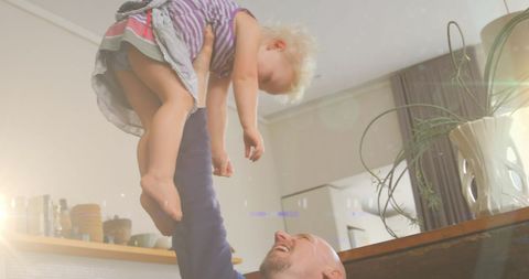 Happy father holding daughter in bright sunny home