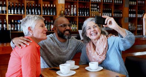 Middle-Aged Friends Enjoying Coffee and Selfie in Cozy Cafe