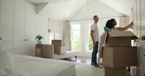 Couple Sorting Belongings in New Home with Moving Boxes Around
