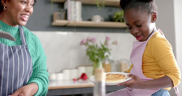 Mother and daughter enjoying cooking pancakes in kitchen - Download Free Stock Images Pikwizard.com