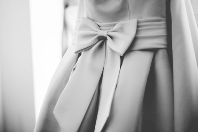 White bridal gown showcasing an elegant bow detail, perfect for use in wedding-related design, bridal fashion inspiration, formal event promotion, or wedding planning guides.