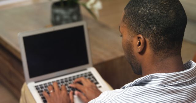 Man focused on his laptop, ideal for content relating to remote work, modern home offices, tech jobs, and digital productivity. Can be used for blogs, articles, advertisements, or websites promoting work-from-home setups, tech solutions, and professional productivity tips.