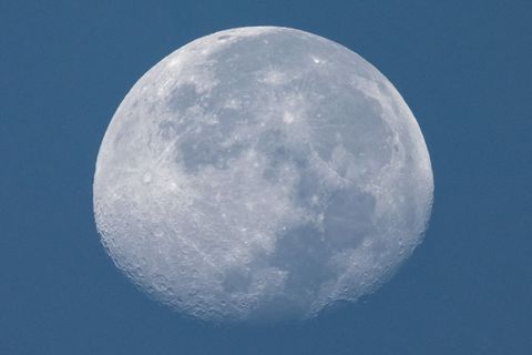Close-up of white moon in daylight against universe blue sky