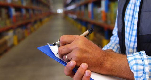 Caucasian man writing on clipboard working in warehouse with copy space. Shipping, delivery, business and work concept, unaltered.