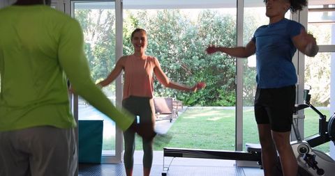 Friends Stretching Together in Light-Filled Gym