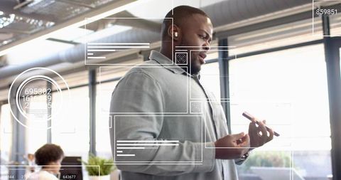 Man using smartphone and wireless earbud in modern open-plan office boosting productivity