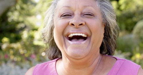 Joyful Senior Woman Laughing Outdoors in Pink Top