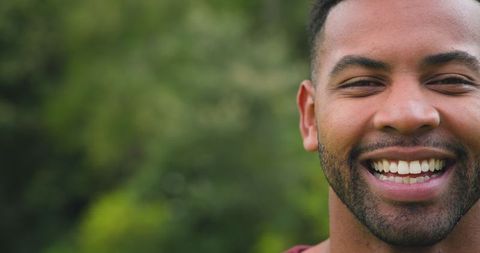 Vibrant man smiling outdoors with nature background