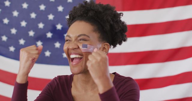 Enthusiastic woman smiling and celebrating with American flag background, showcasing pride in nationality. Perfect for content on patriotism, national holidays, cultural celebrations, or American identity.