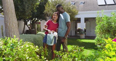 Couple enjoying gardening in sunny front yard garden