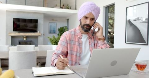 Sikh man multitasking in home office working remotely