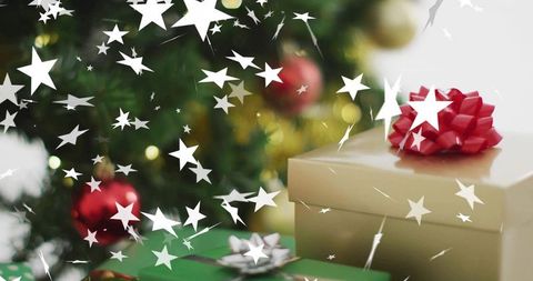 Gold gift box with red bow and star confetti, christmas present with tree bokeh