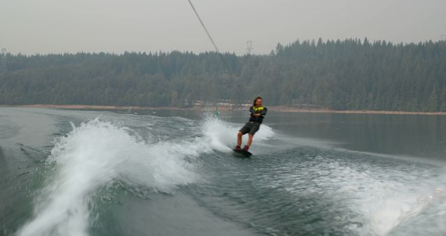 Man Wakeboarding on Lake with Forest in Background - Download Free Stock Images Pikwizard.com