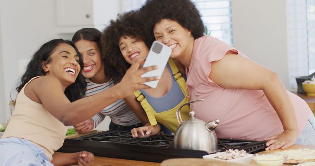 Group of multiethnic friends taking selfie in kitchen, showing joy and togetherness. Perfect for content on social bonding, lifestyle, diversity, cooking experiences, and creating lasting memories.