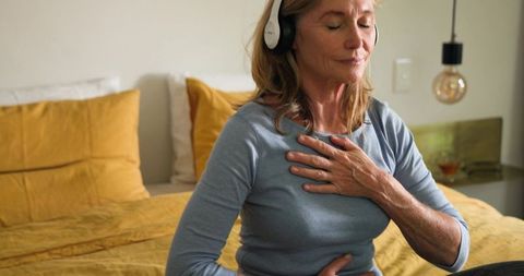 Senior Woman Mindfully Meditating with Headset in Bedroom