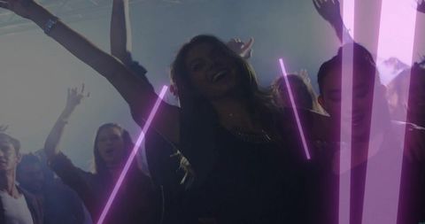 Woman dancing under magenta neon beams in crowded nightclub, joyful nightlife energy