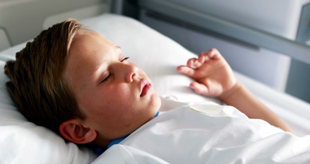 Child peacefully sleeping in hospital bed, indicating recovery from illness. Suitable for use in healthcare communication materials, articles on pediatric care, medical blogs, and wellness resources. Can also be useful for illustrating information on child recovery, hospital environment, rest, and healing.