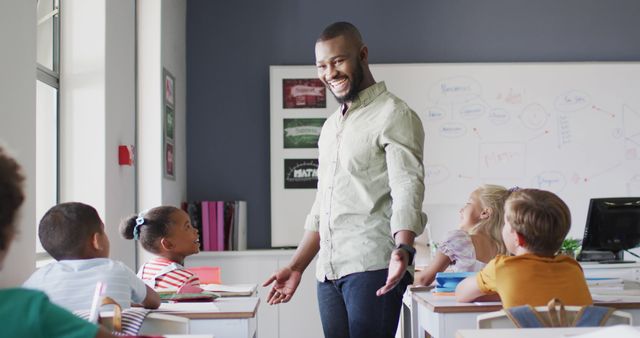 Male teacher engaging with diverse group of elementary school students in classroom. Ideal for educational content, schooling brochures, teacher training materials, youth mentorship, school advertisements, and academic programs.