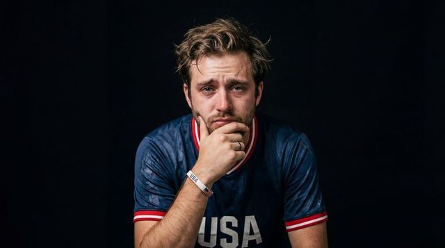 Somber sports fan holding chin wearing usa jersey and wristband cinematic portrait