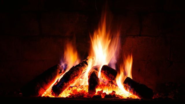Wooden logs burning brightly in a fireplace, creating a cozy and warm atmosphere. Perfect for themes related to winter comfort, home decoration, relaxation scenes, or promoting heating services.