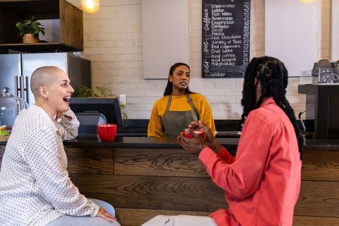 Friends chatting with indian barista at cozy coffee counter for cafe lifestyle