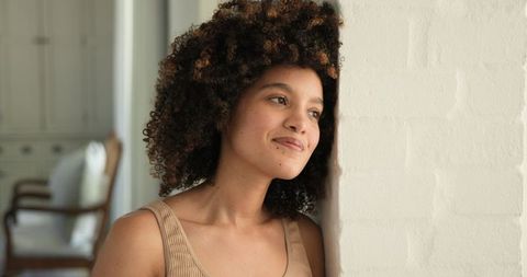 Thoughtful Woman Leaning Against Brick Wall Indoors