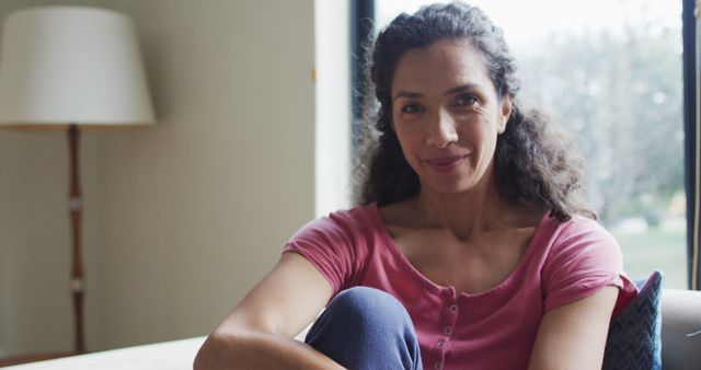 Portrait of happy biracial woman ,sitting living in room. domestic life and leisure time concept.
