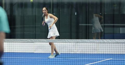 Female Tennis Player Swinging Racket on Blue Synthetic Court