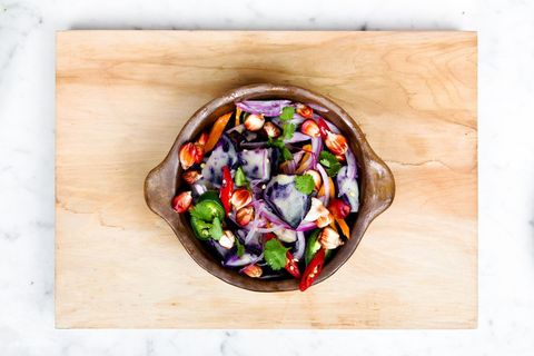 Colorful purple potato salad with red onion, chilies and cilantro on wooden board