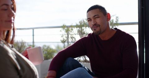 Friends Enjoying Coffee on Sunny Rooftop Balcony in Urban Setting