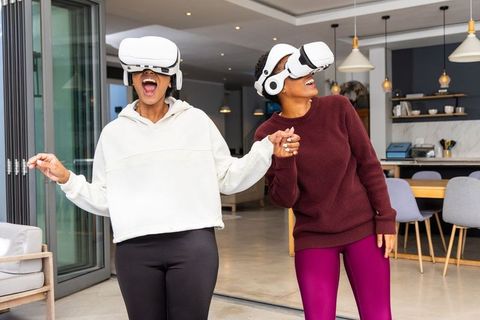 African american and indian women experiencing virtual reality together in modern home