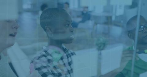 Team collaborating on glass whiteboard with sticky notes in modern office