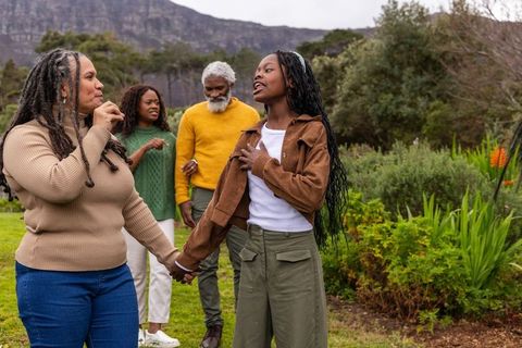 Multigenerational african american family walking hand-in-hand in garden landscape