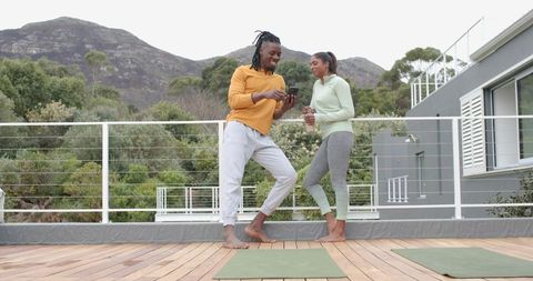 Diverse couple sharing rooftop workout moment with smartphone and yoga mats