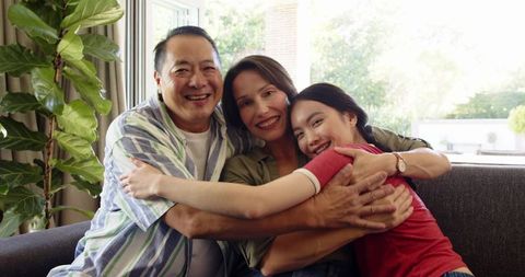 Happy Family Embracing on Sofa with Lush Greenery Backdrop